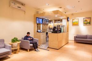 a man sitting in a chair in a waiting room at 7Days Premium Guangzhou Kecun Subway Station in Guangzhou