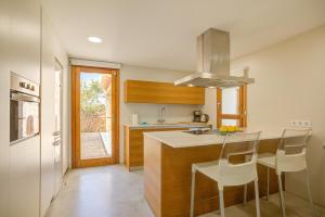 a kitchen with a counter with chairs and a sink at Can Cadernera by Rentallorca in Can Picafort