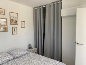 sypialnia z łóżkiem i szarymi zasłonami w obiekcie Le Clos des Hautes Mers w mieście Talmont-sur-Gironde
