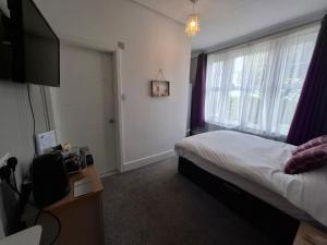 a bedroom with a bed and a tv and a window at Westbrook Lodge Guest House in Margate