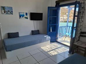 a bedroom with a bed and a balcony with a television at Vrahos Rooms - Studios in Alopronia