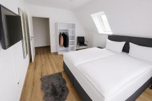 a bedroom with a large white bed and a tv at Ulm City Appartement in Ulm