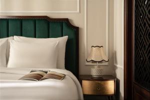 a bedroom with a bed with a green headboard and a lamp at GM Premium Hotel in Hanoi