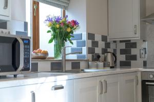 eine Küche mit einer Vase mit Blumen auf einer Theke in der Unterkunft Yew Cottage in Boston