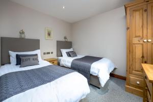 ein Schlafzimmer mit zwei Betten und einem Holzschrank in der Unterkunft Yew Cottage in Boston