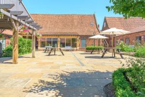 eine Terrasse mit Picknicktischen und Sonnenschirmen in der Unterkunft Yew Cottage in Boston + 6 Fotos