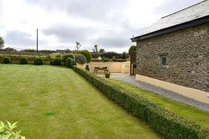 a person sitting on a bench in a yard at Oak Cottage in Tregoney