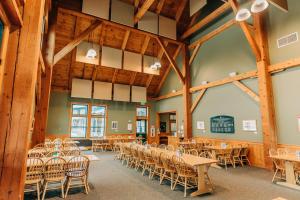 a banquet hall with tables and chairs in a room with wooden beams at Highland Center in Bretton Woods