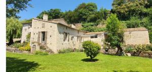 an old stone house with a tree in the yard at le moulin d'âne à niort in Niort