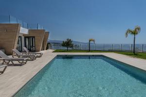 a swimming pool with chairs and a house at Casa Vista Azul la Herradura Punta de la Mona in Almuñécar