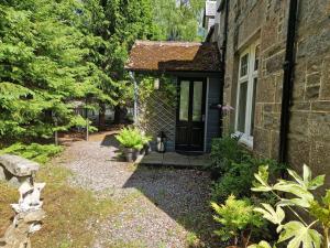 a stone house with a black door in a yard at Eagle View Guest House in Newtonmore