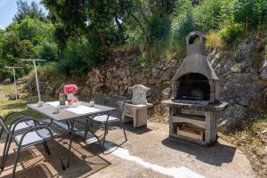 a outdoor oven and a table with a table and chairs at Holiday Home Casa Blu near the Beach in Neum