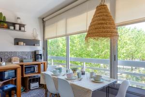 ein Esszimmer mit Tisch und Stühlen und einem großen Fenster in der Unterkunft Chez Stéphanie De - Superbe studio design en centre ville avec piscine in La Grande-Motte