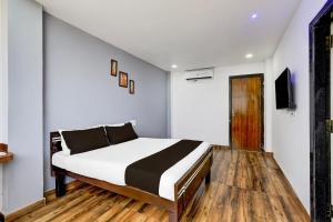 a bedroom with a bed and a tv on a wall at Hotel O PRAMOD GUEST INN in Nellore