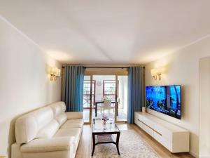 a living room with a couch and a tv at Luxury unique central flat with 2 swimming pools in Playa de las Americas