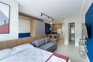 a bedroom with a bed and a couch and a kitchen at SPA - Studios incríveis em Floripa-SC in Florianópolis