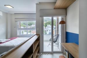 a bedroom with a bed and a desk with a chair at SPA - Studios incríveis em Floripa-SC in Florianópolis