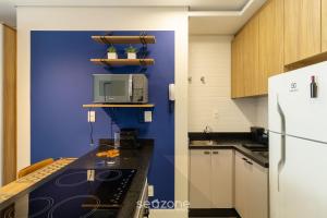 a kitchen with a blue wall and a white refrigerator at SPA - Studios incríveis em Floripa-SC in Florianópolis