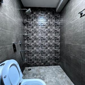 a bathroom with a toilet and a tiled wall at JNS Roost in Gurgaon