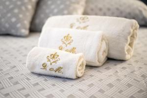 three towels with gold embroidery sitting on a bed at Bed & Breakfast Villa Michela Alezio in Alezio +120 photos