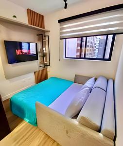 a bedroom with a bed with a couch and a tv at Novinho, Lindo e Moderno C/ Ar Cond. in Curitiba