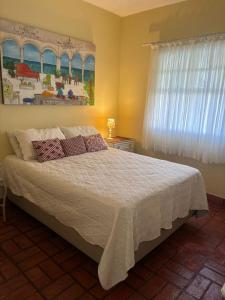 una camera da letto con un letto e un quadro sul muro di Casa Região Privilegiada próx. ao Centro e Clube Campo. a Joanópolis