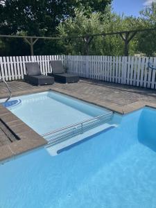 a swimming pool with two chairs and a white fence at Lohals camping in Tranekær