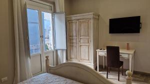 Zimmer mit einem Schreibtisch, einem TV und einem Fenster in der Unterkunft Giully's Rooms in Catania