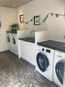 a laundry room with two washing machines and a sink at Lohals camping in Tranekær