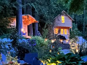 a small house with lights in a garden at night at Creekside Bunkies in Roberts Creek