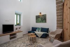 un salon avec un canapé bleu et une télévision dans l'établissement Nouvelle15 Cozy House with Private Pool, à Koskinou