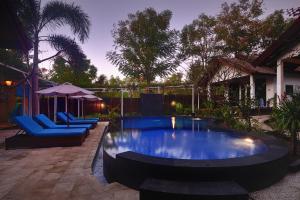 a swimming pool in a yard with two chairs and an umbrella at Wah Danima Resort & Restaurant in Gili Trawangan