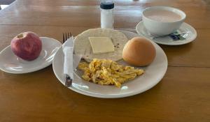 a plate of breakfast food with an egg and an apple at El Palmar in Caucasia