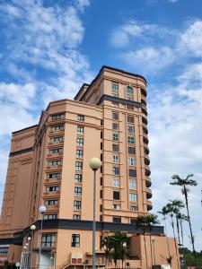 a tall tan building with palm trees in front of it at Riverbank Suites Kuching Waterfront in Kuching