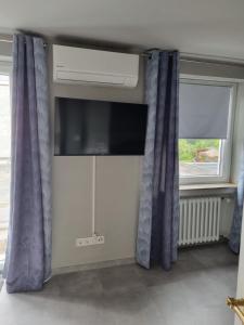 a room with two windows with curtains and a television at Appartement im weißen Haus in Moers +5 photos
