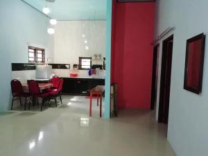 Kota BharuにあるUMARI WEDDING HOMESTAY & SPA CONCEPT in KOTA BHARUの赤い壁の客室で、テーブルと椅子が備わります。
