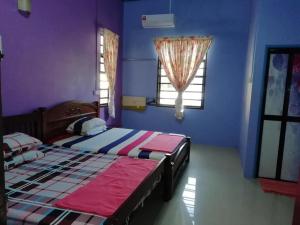 Kota BharuにあるUMARI WEDDING HOMESTAY & SPA CONCEPT in KOTA BHARUの紫の壁のベッドルーム1室(ベッド2台付)