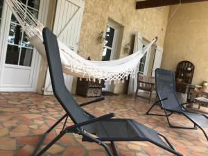 a hammock in a patio with two chairs and a table at Maison de vacances Bazas in Lignan-de-Bazas