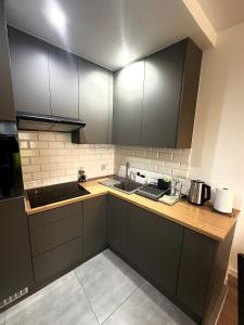 a kitchen with black cabinets and a sink at Apartament Nad Stawem in Wadowice