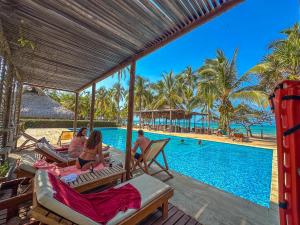 eine Gruppe von Personen, die an einem Pool auf Stühlen sitzen in der Unterkunft Huku Beach Hostel in Palomino
