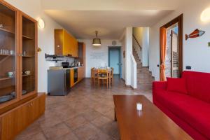 a living room with a red couch and a kitchen at GuestHost - Bedà House in Porto Carollo