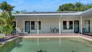 a house with a swimming pool in front of it at Poolside Palms Villa in Trinity Beach +26 photos
