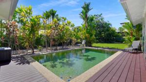a swimming pool in a backyard with a wooden deck at Poolside Palms Villa in Trinity Beach