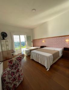 una habitación de hotel con dos camas y una silla en Recanto Vista do Valle, en Mairiporã