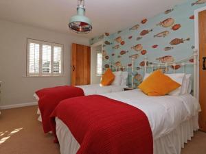 Un dormitorio con dos camas con sábanas rojas y blancas. en Trelan, en St Austell