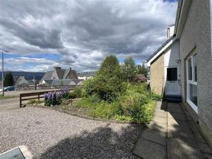 a house with a yard with flowers and a fence at Lomond Villa in Fort William