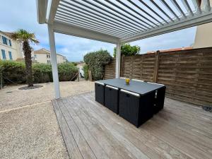 a patio with a black table under a pergola at Entre mer & piscine Maison familiale pour 6 in Brétignolles-sur-Mer