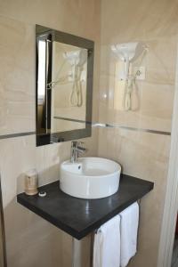 a bathroom with a sink and a mirror and towels at Hôtel De France in Boulogne-Billancourt +30 photos