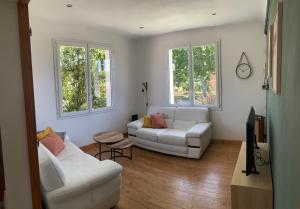 a living room with two white couches and two windows at La villa Jeanne- Charmante maison avec très belle terrasse couverte à 10 min du centre de Salies de Bearn in Lahontan