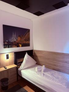 ein Schlafzimmer mit einem Bett und einem Bild einer Brücke in der Unterkunft Niehler Hotel in Köln